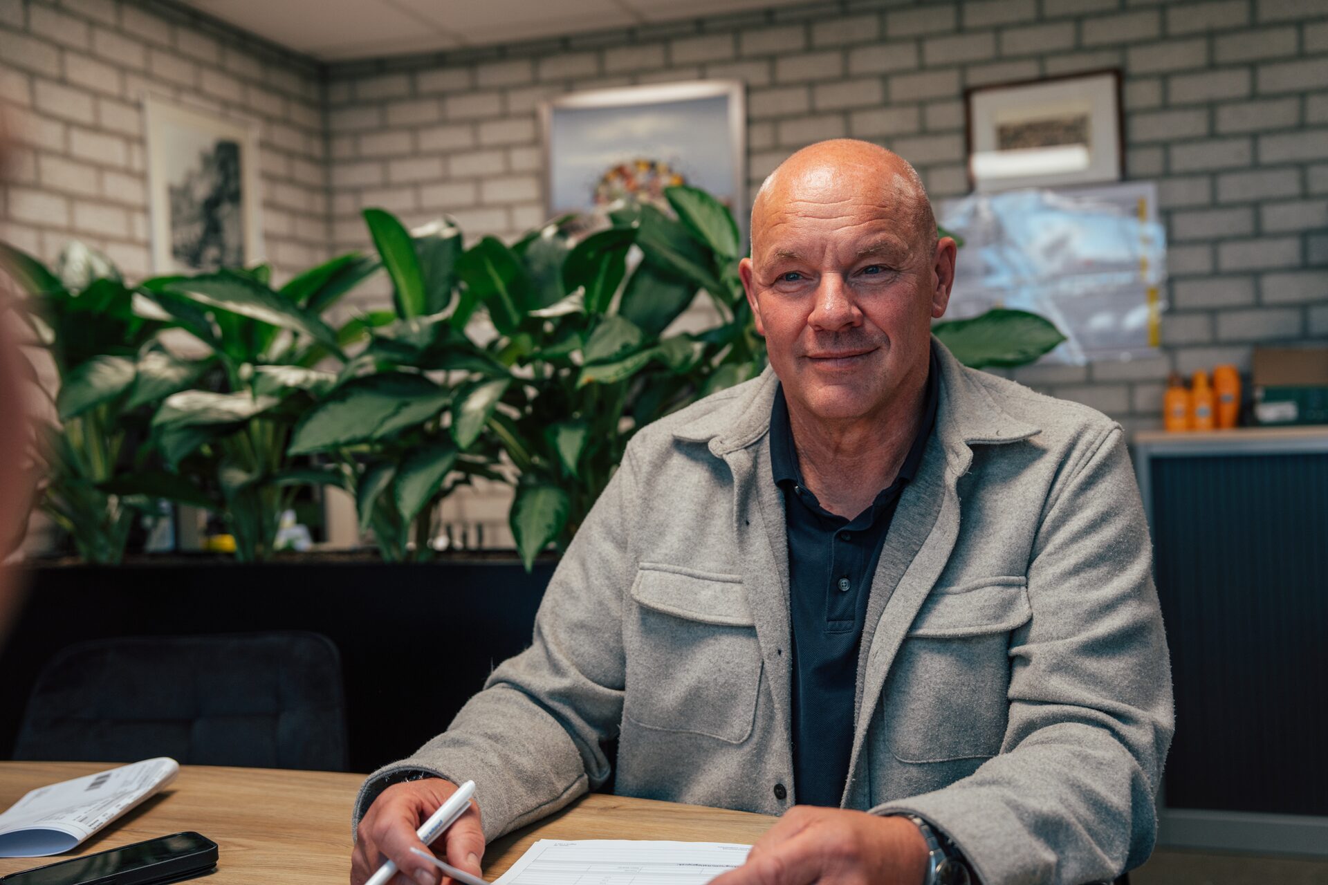 Medewerker van Van Olm Elektrotechniek met pen en formulier aan de overlegtafel op kantoor.