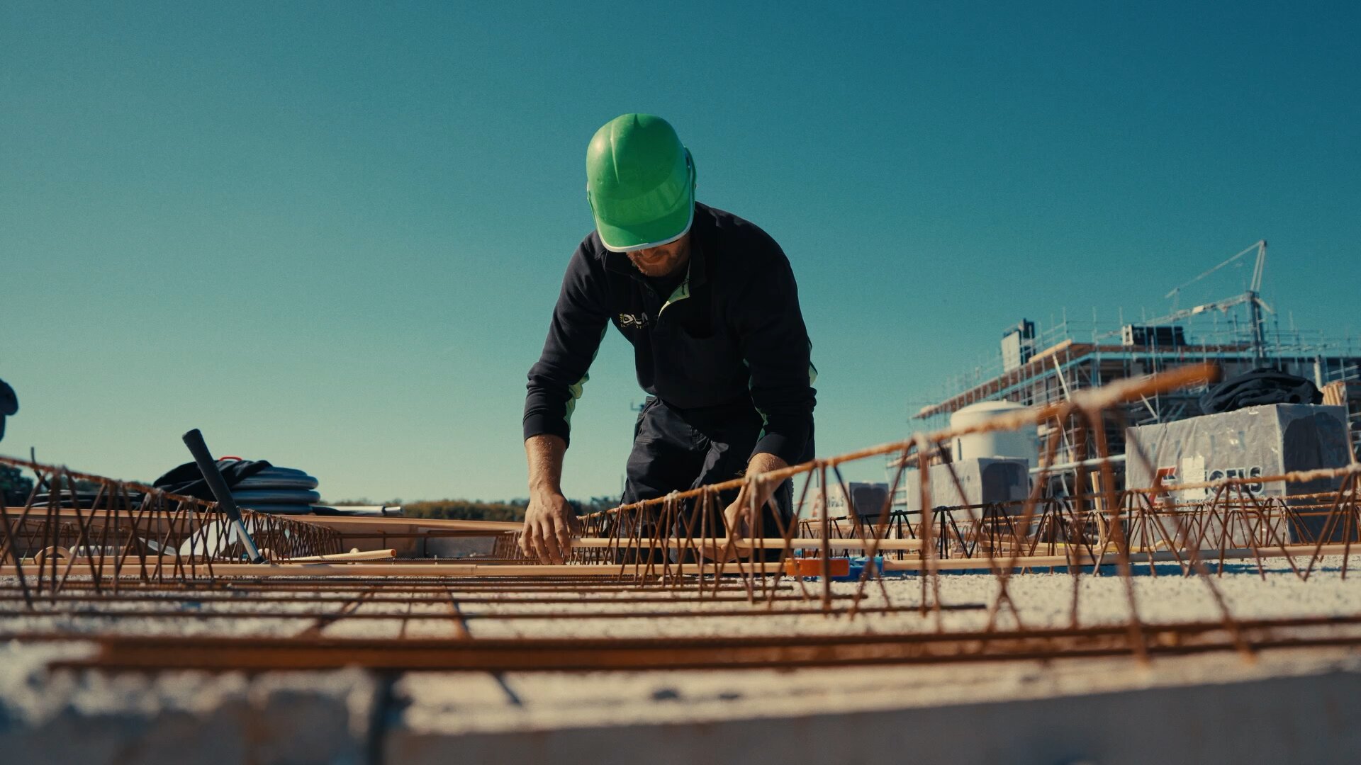 Monteur legt installatiebuizen tussen de wapening van een vloer in aanbouw.